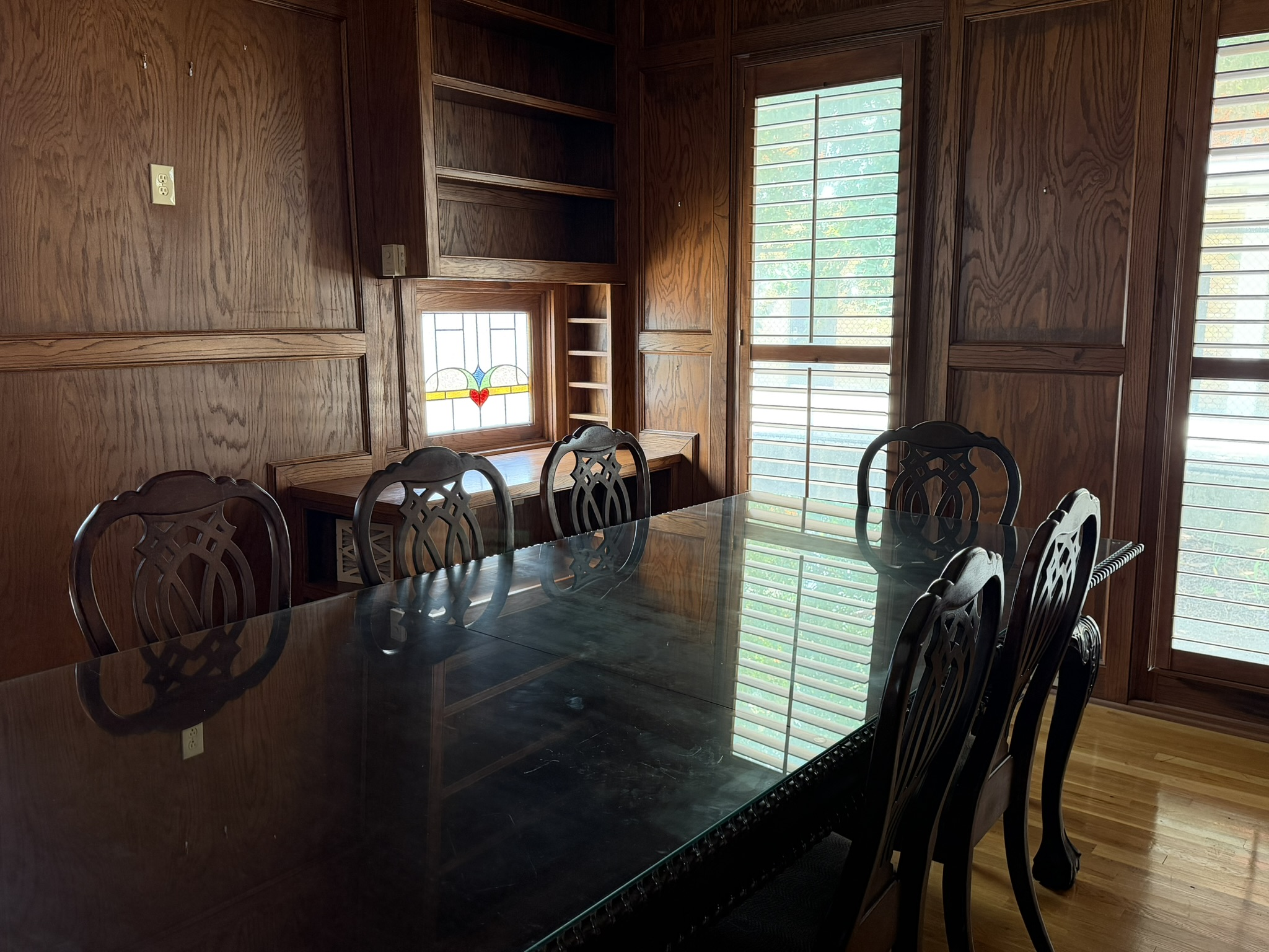 A large wooden table with chairs in a wood-paneled room.